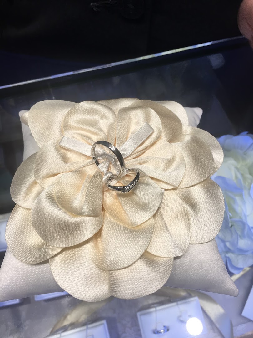 Two rings displayed on a decorative pillow in a jewelry case.