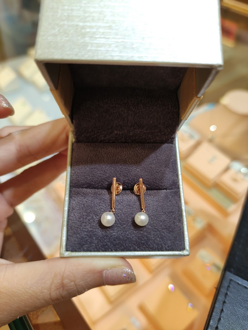 Hand holding open jewelry box with pearl earrings inside.