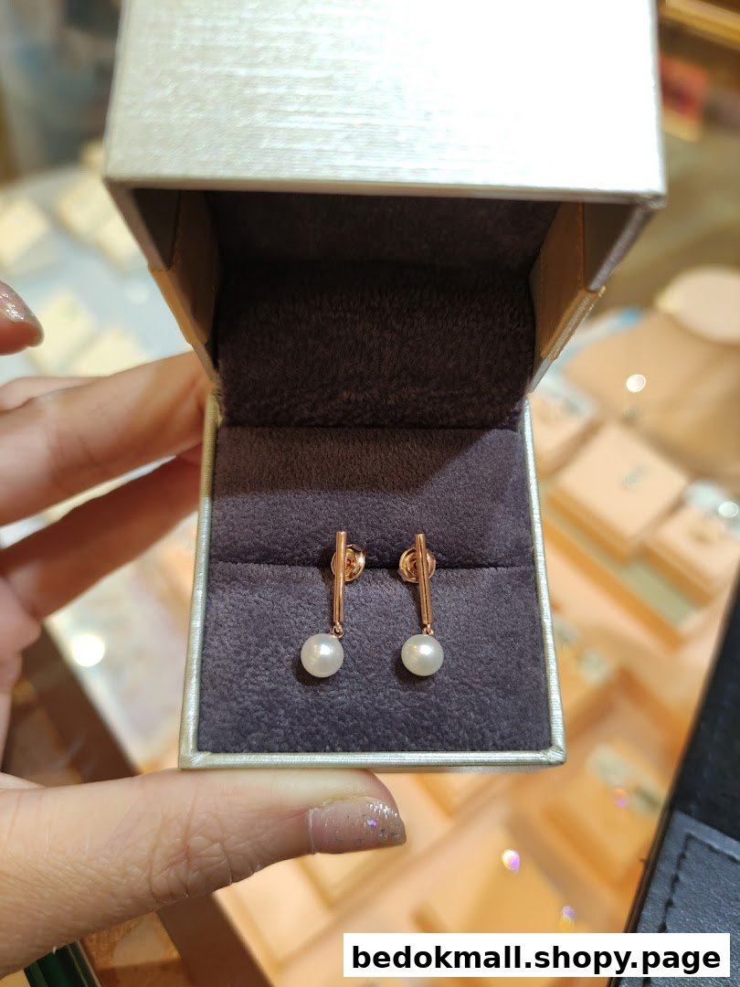 Hand holding open jewelry box with pearl earrings inside.