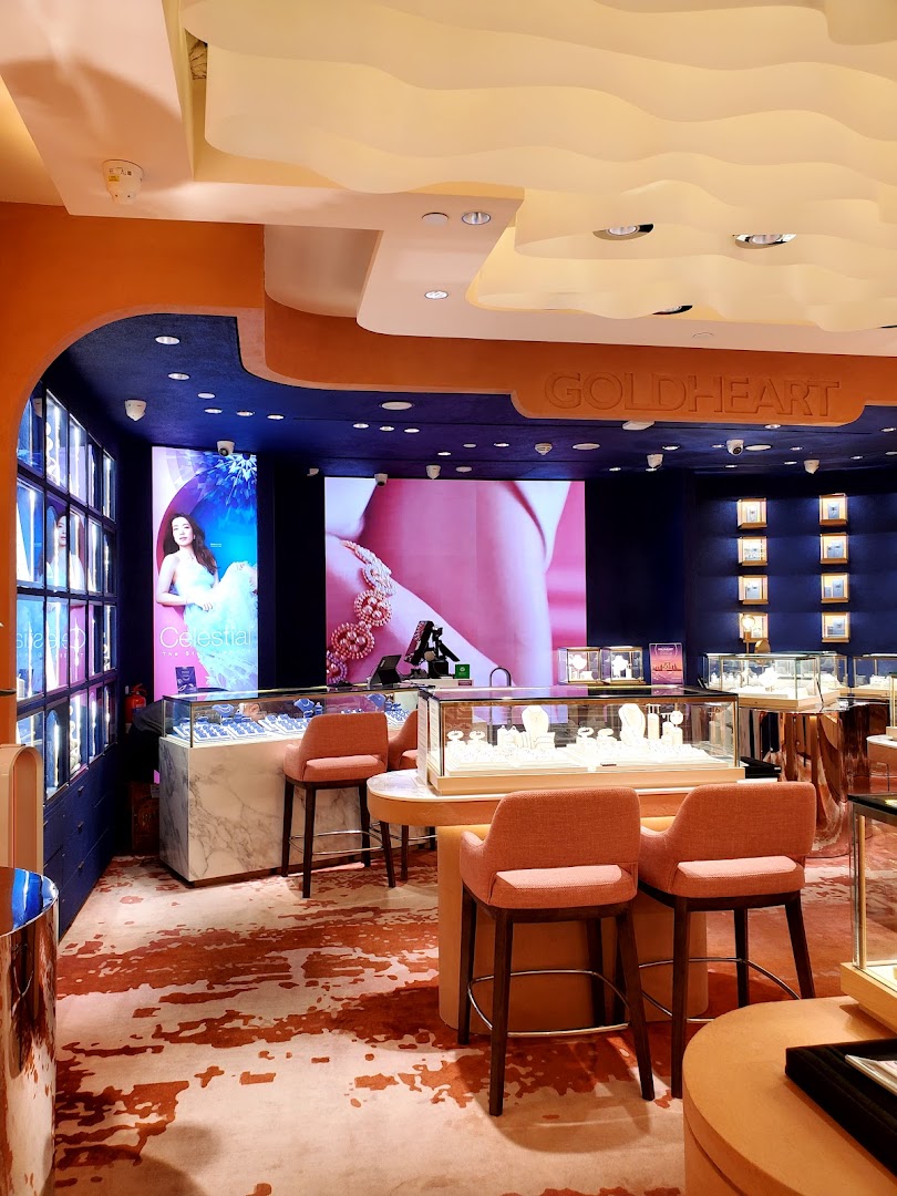 Interior view of a Goldheart Jewelry shop with displays, screens, and seating.