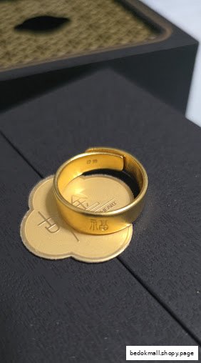 Close-up of a gold ring with engravings on a dark display surface.