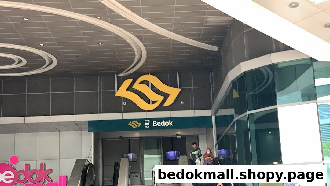 Entrance to Bedok transport hub with escalators and people.