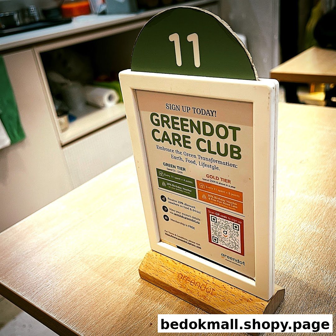 Table stand displaying Greendot Care Club loyalty program details with a QR code.