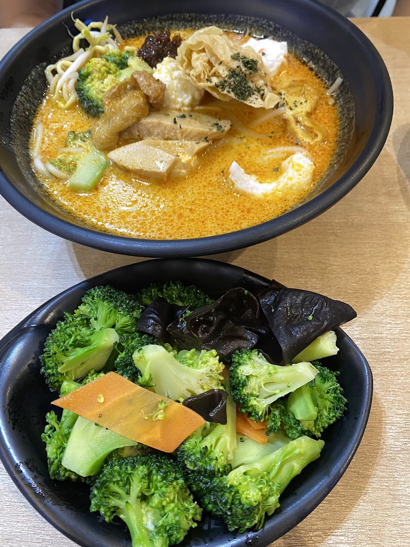Two bowls of food: a noodle dish with broth and a side of broccoli.