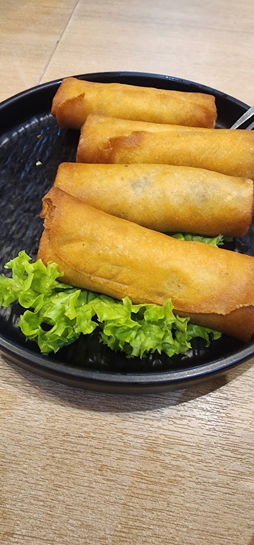 Fried spring rolls on a black plate with lettuce.