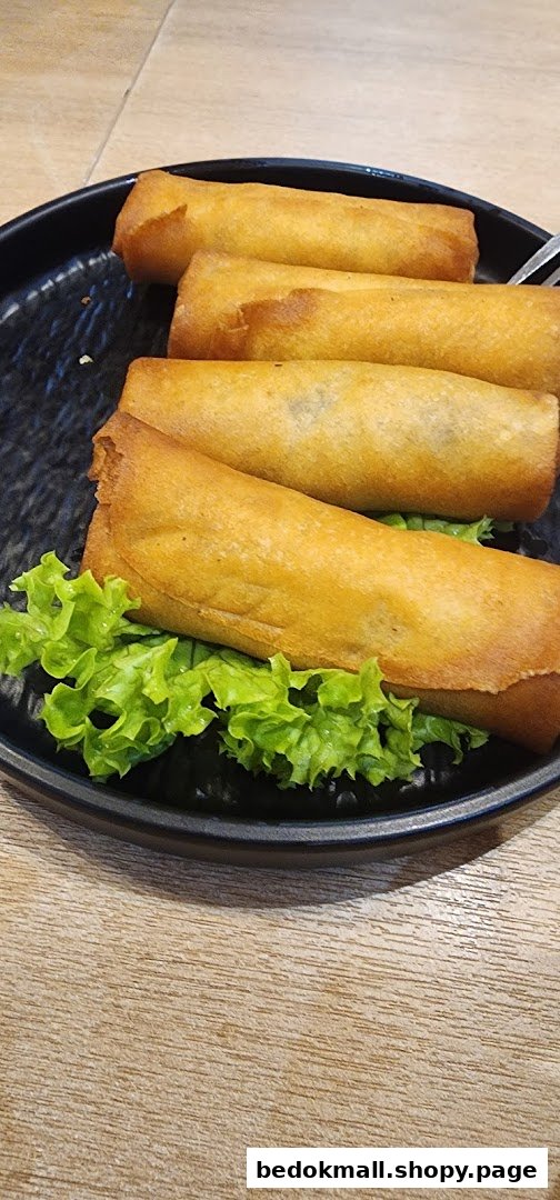 Fried spring rolls on a black plate with lettuce.