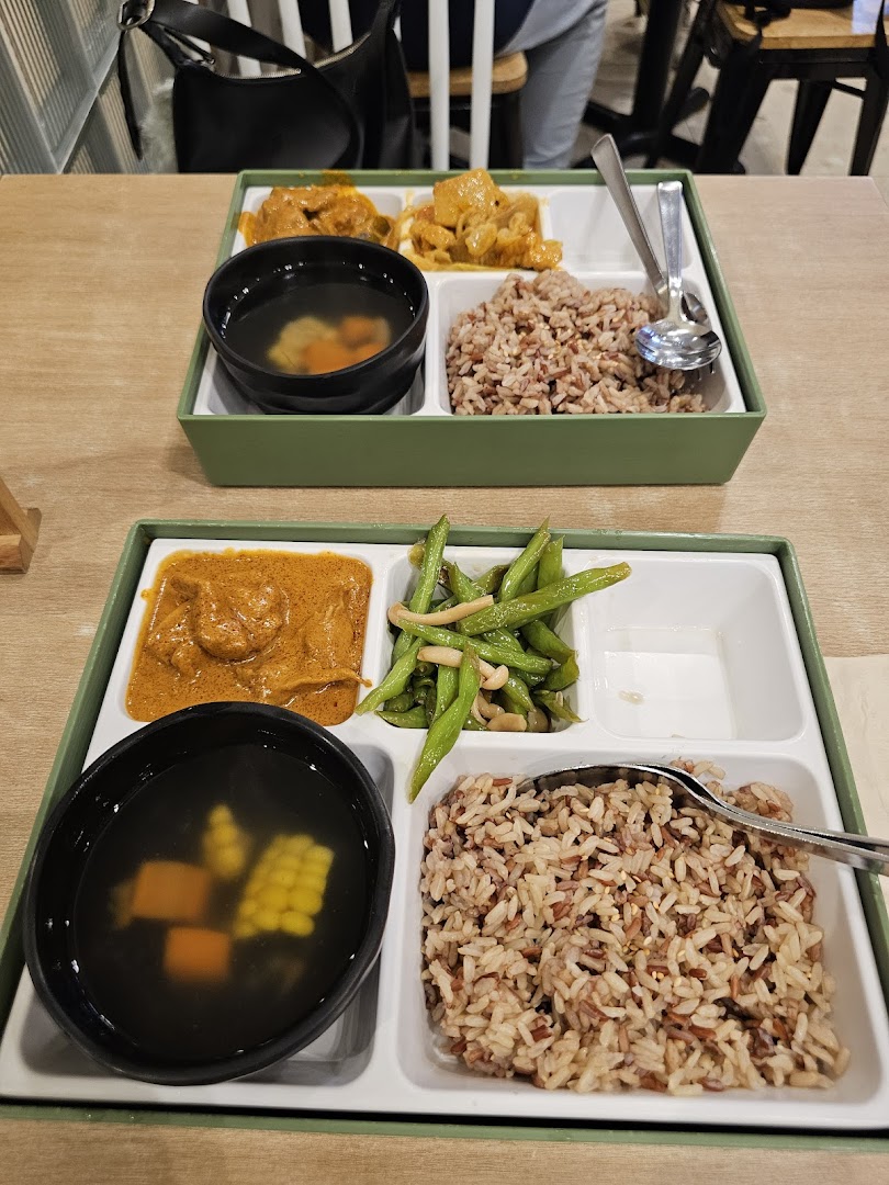 Two bento-style trays of food with rice, curry, soup, and vegetables.