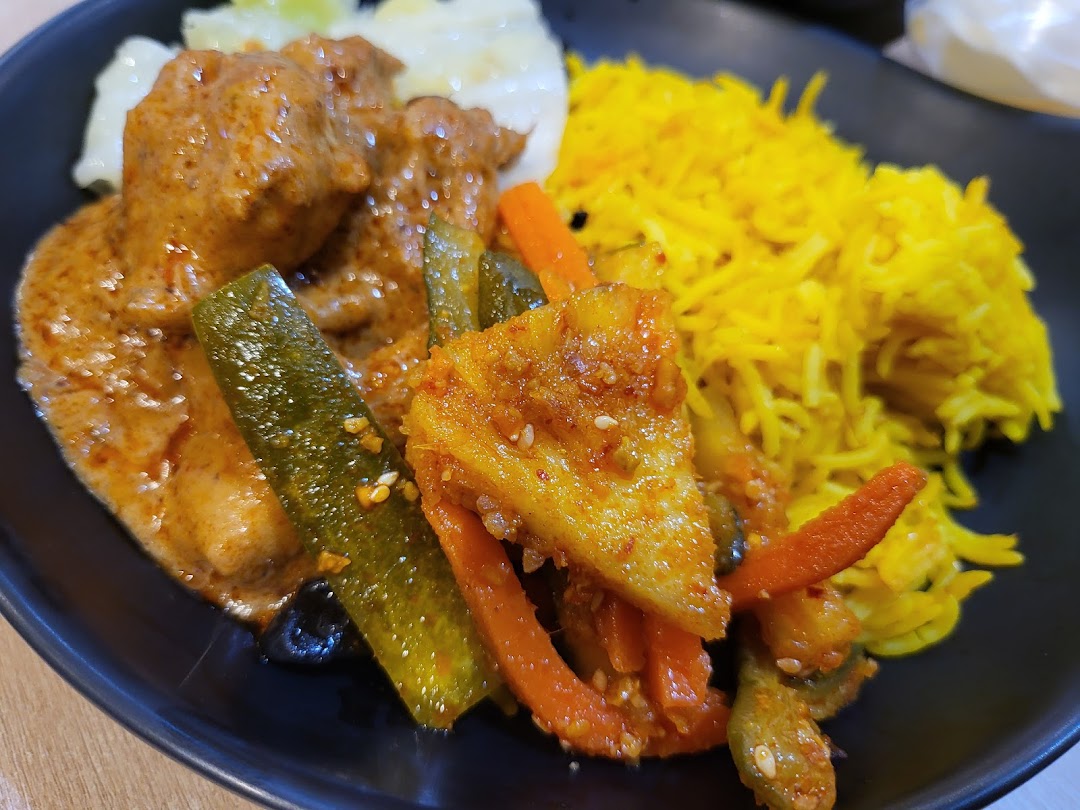 A plate of yellow rice, curry, and mixed vegetables.