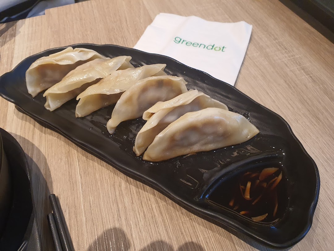 A plate of dumplings with dipping sauce on a wooden table.