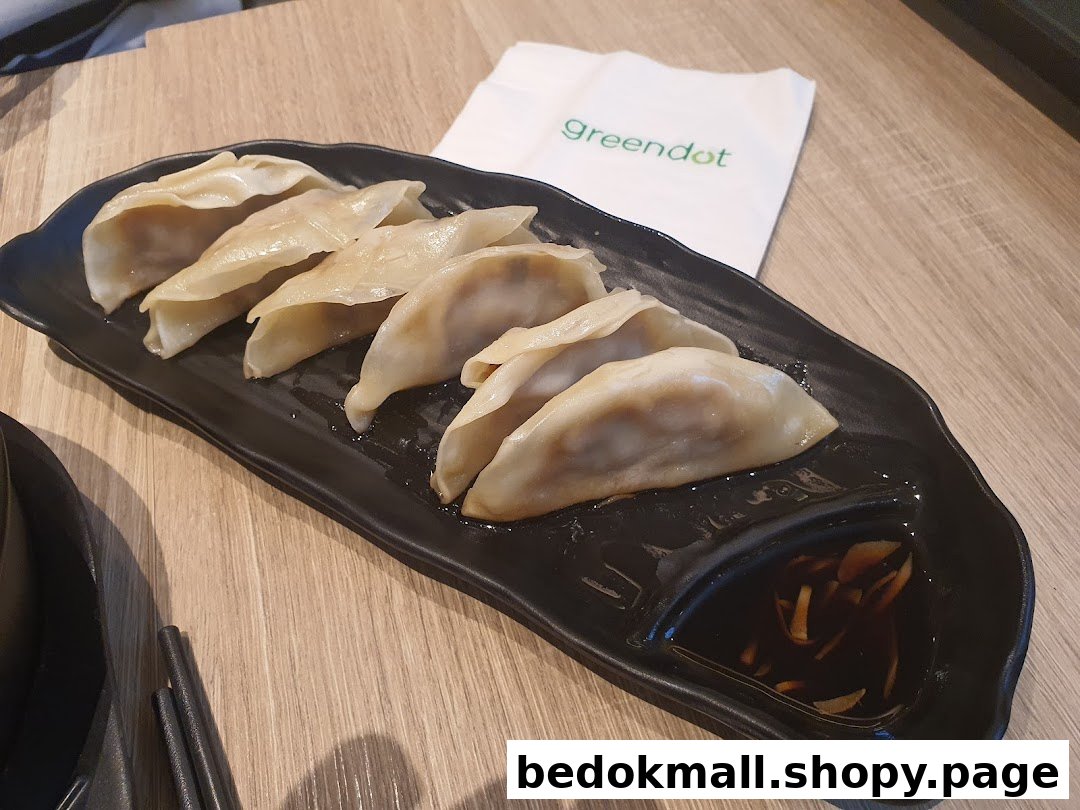 A plate of dumplings with dipping sauce on a wooden table.