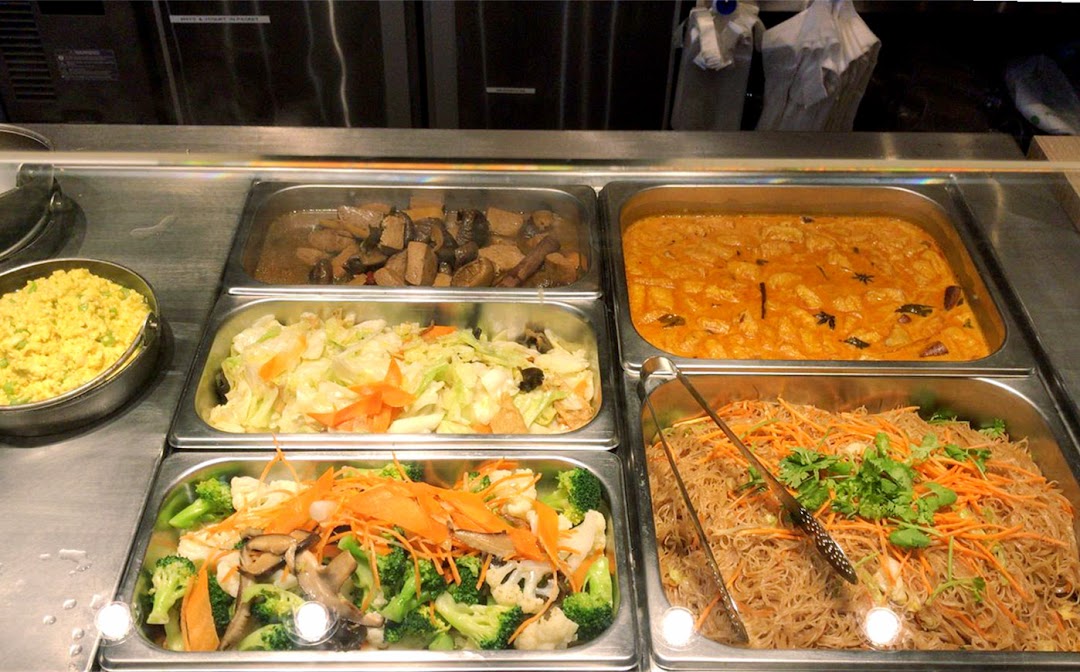 Multiple food trays with various dishes on a serving counter.