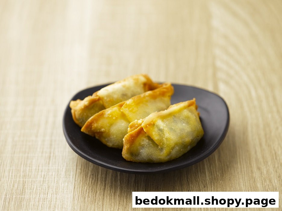 Four fried dumplings are served on a black plate on a wooden surface.
