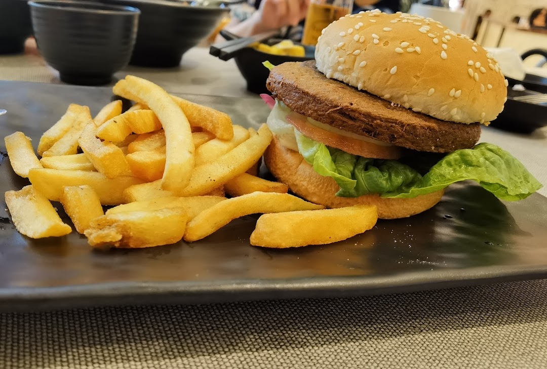 A burger and fries on a black plate, served in a restaurant setting.