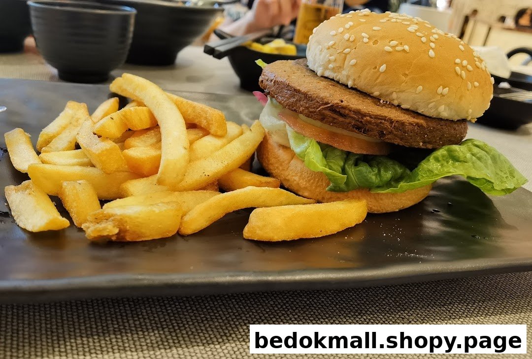 A burger and fries on a black plate, served in a restaurant setting.