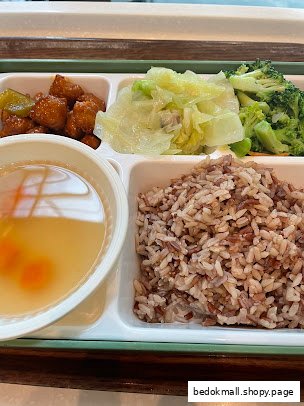 A meal with brown rice, soup, vegetables, and a main dish on a segmented tray.
