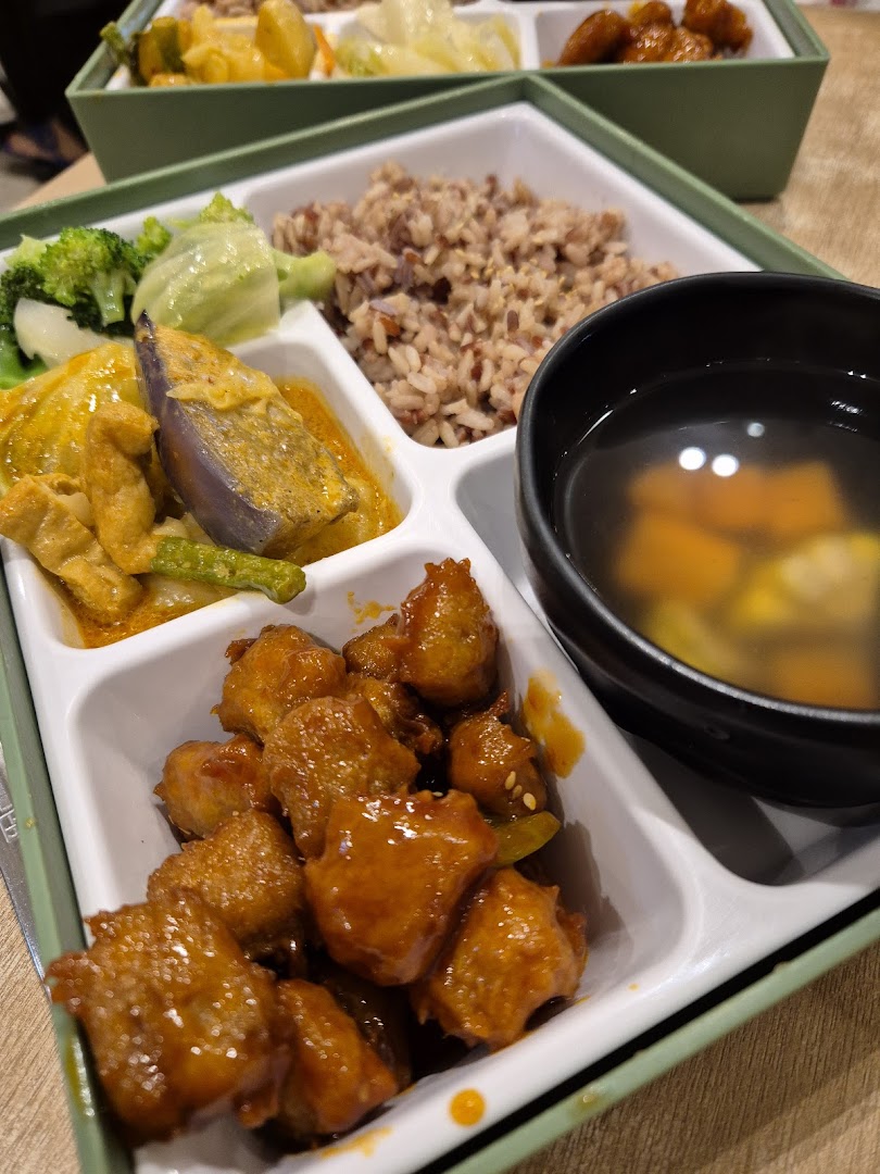 A bento box meal with rice, vegetables, nuggets, and soup.
