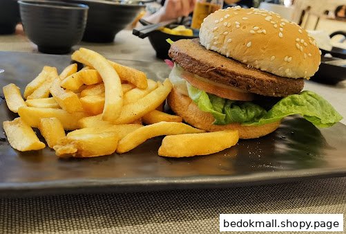 A burger and french fries are served on a black plate.
