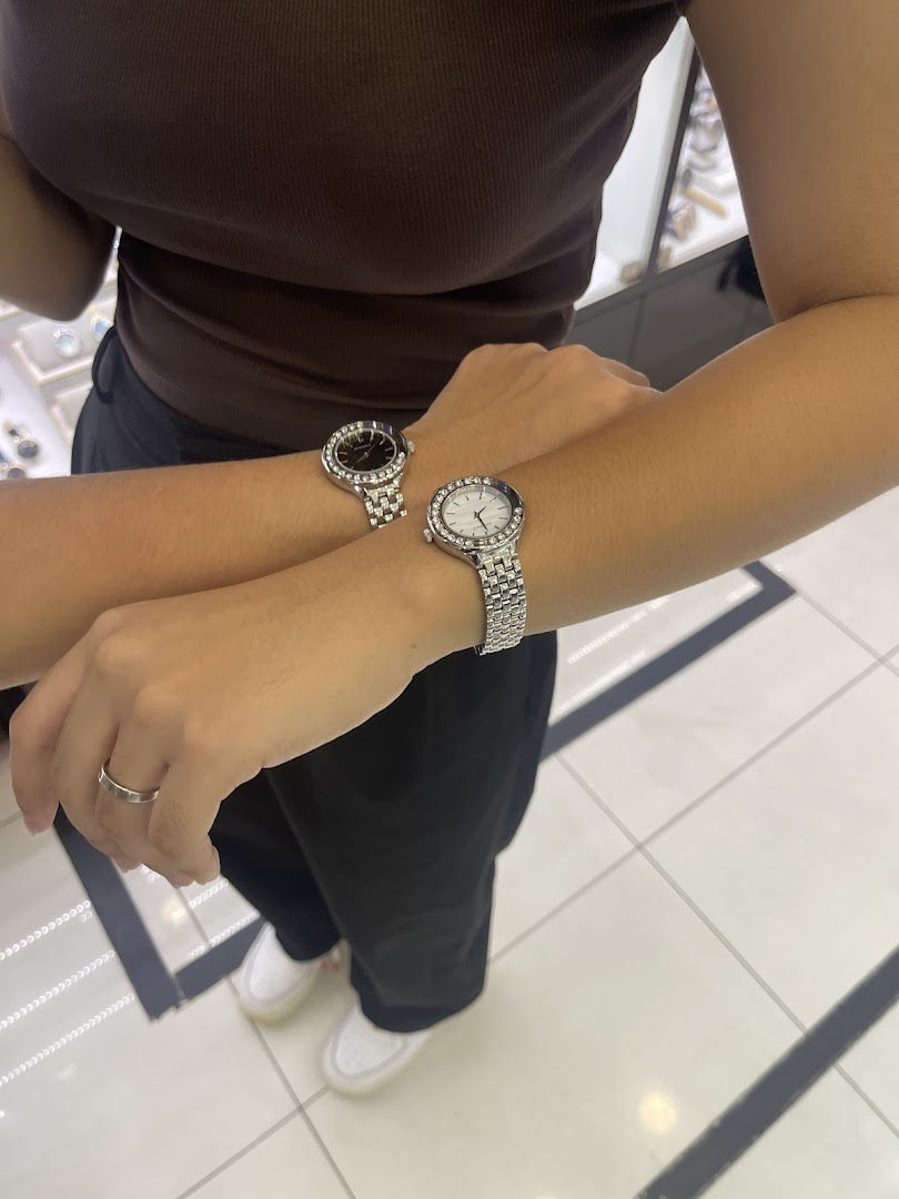 Two people's arms wearing watches in a retail shop setting.