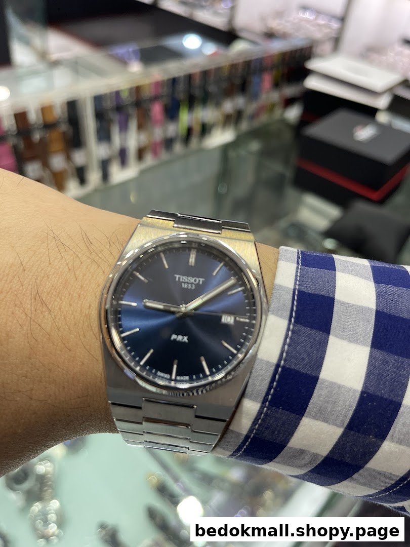 A person's arm wearing a watch, with blurred shop interior in the background.