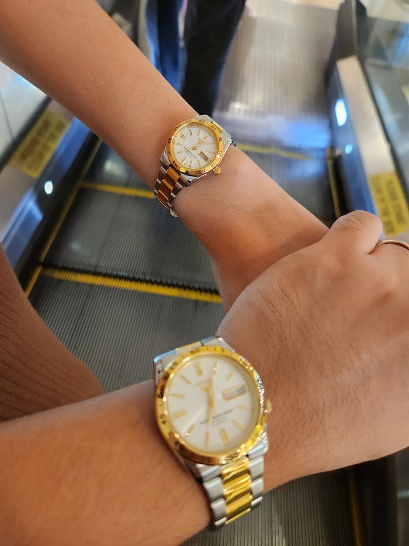 Two people wearing watches on an escalator.