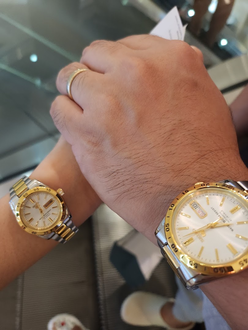 Two people wearing gold and silver watches on their wrists.
