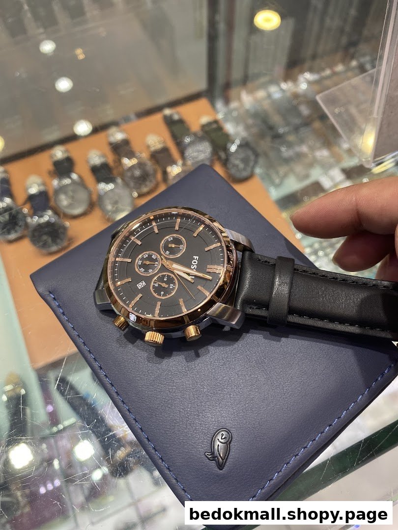 Close-up of a Fossil watch on a blue wallet, with other watches in background.