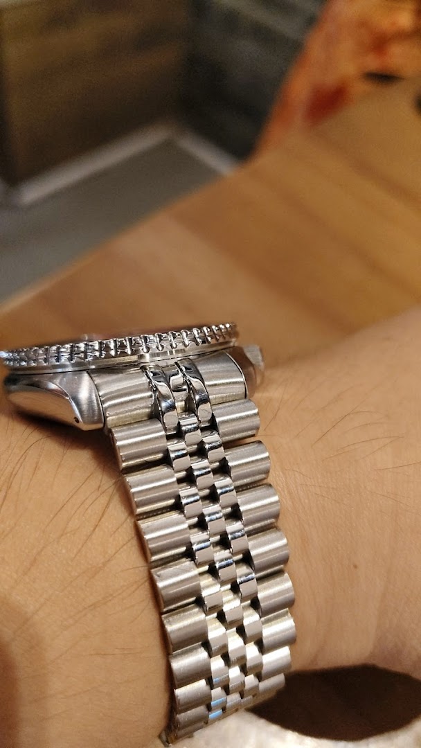 Close-up of a silver watch with a metal bracelet on a person's wrist.