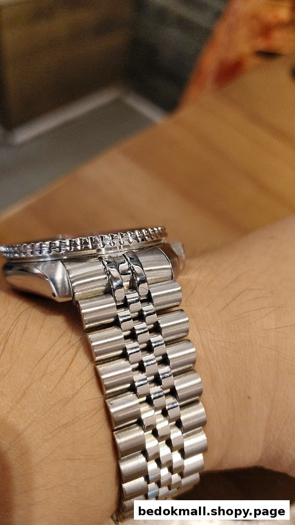 Close-up of a silver watch with a metal bracelet on a person's wrist.