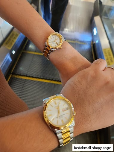 Two people wearing watches on an escalator.