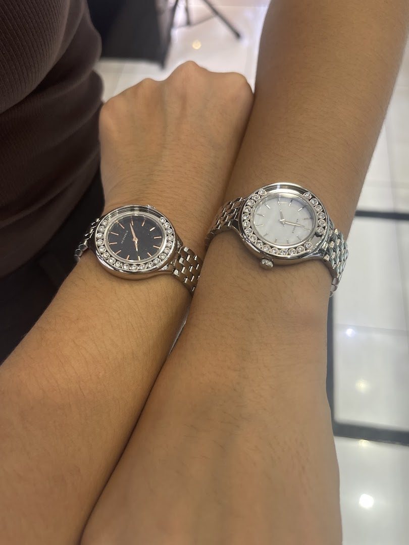Two arms wearing silver watches with crystal bezels.