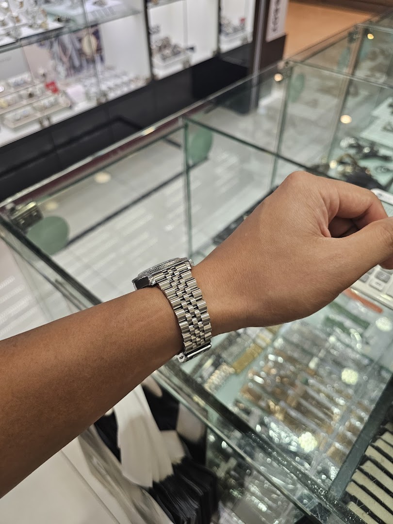 Person's arm wearing a watch inside a shop with display cases.