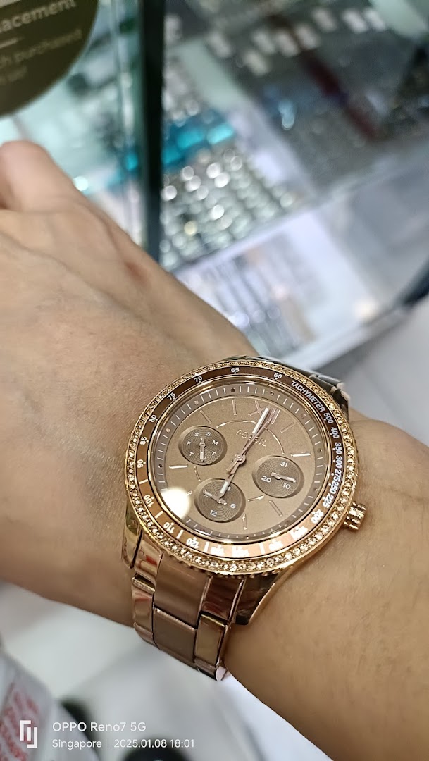 Close-up of a rose gold watch with a diamond bezel on a person's wrist.