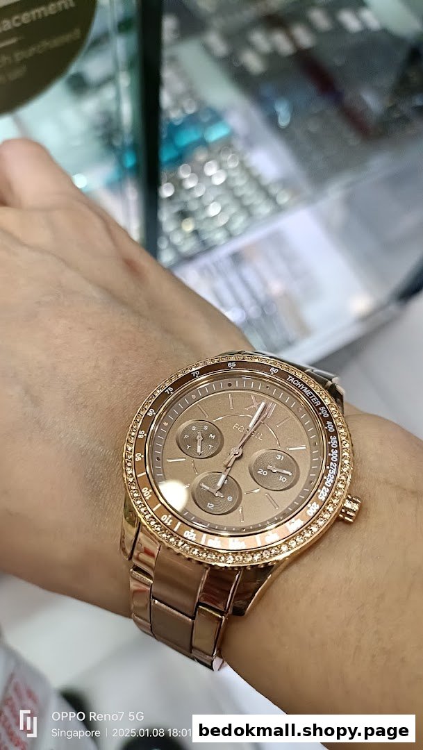 Close-up of a rose gold watch with a diamond bezel on a person's wrist.