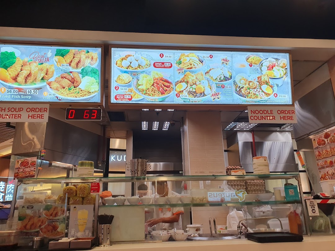 Food stall counter with large menu boards displaying various dishes and prices.