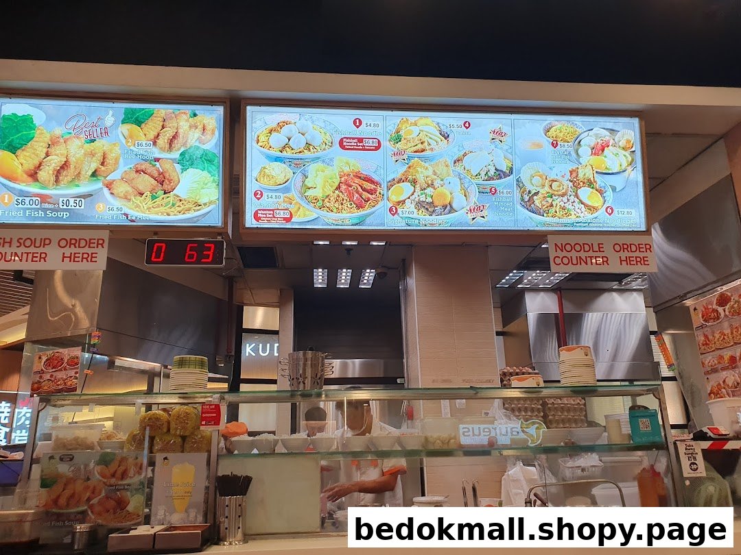 Food stall counter with large menu boards displaying various dishes and prices.