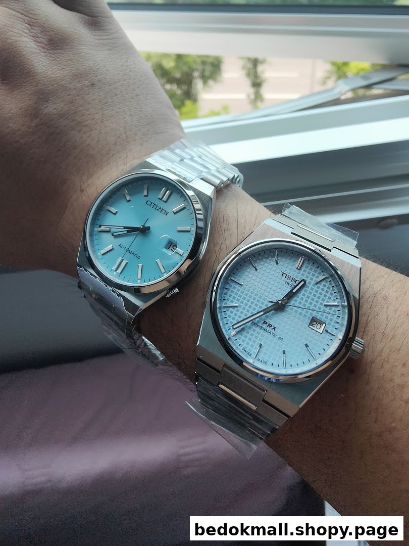 Two light blue dial watches, Citizen and Tissot, on a person's arm.