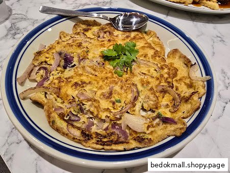 A plate of omelet with red onions and cilantro on a marble table.