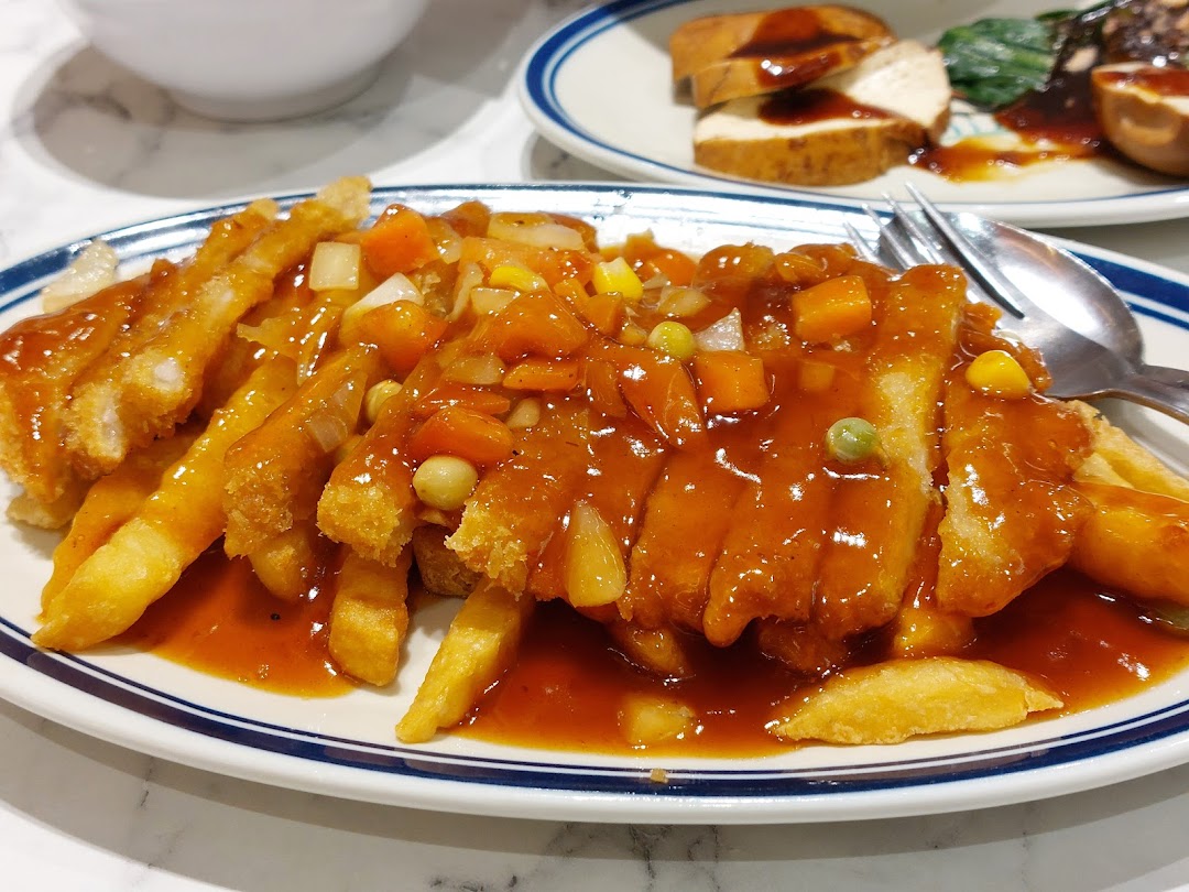 A plate of fried cutlets and fries with sweet and sour sauce.