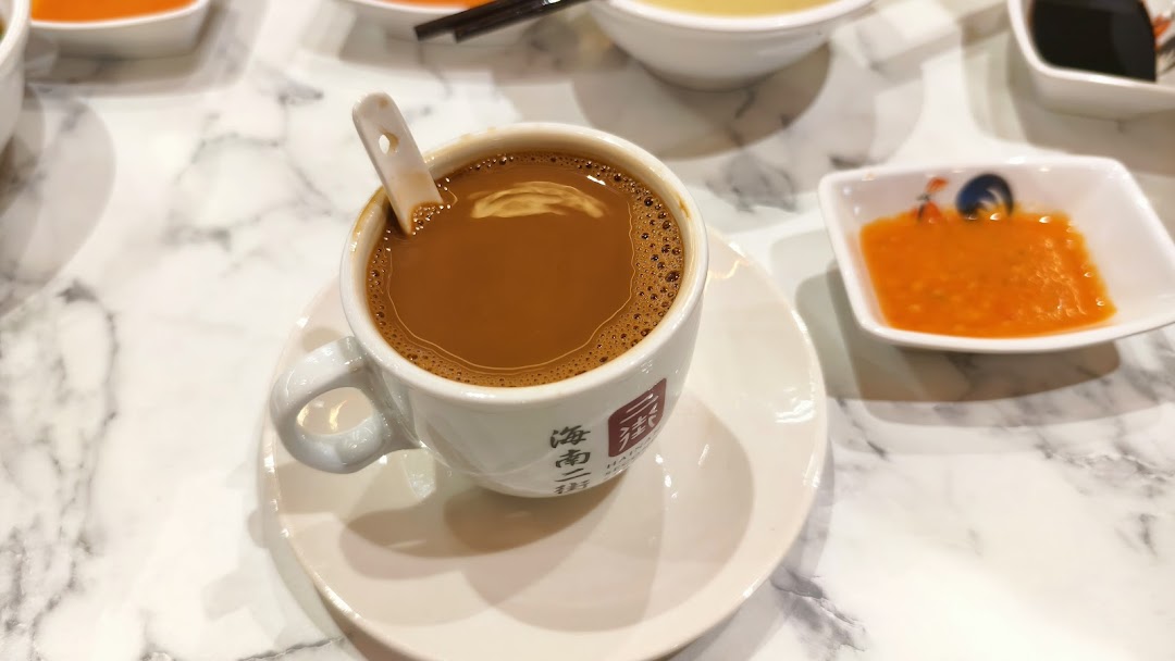 A cup of coffee/tea on a marble table with sauces.
