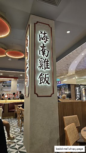 Interior view of a restaurant with a large illuminated sign on a pillar.