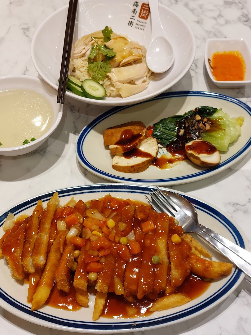 A table with multiple dishes of food, including chicken rice and fried items.