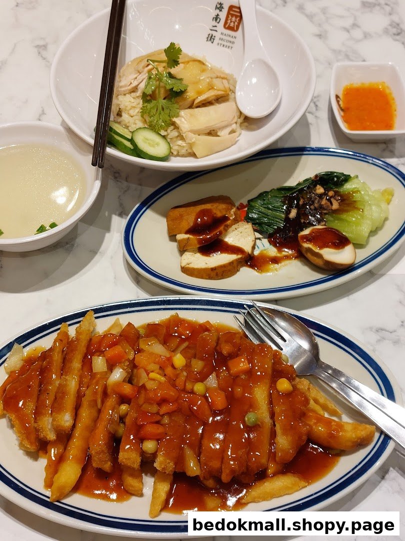 A table with multiple dishes of food, including chicken rice and fried items.