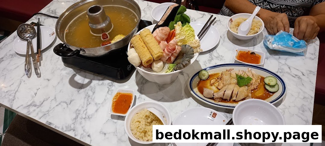 A table with hotpot, various ingredients, Hainanese chicken, and rice.