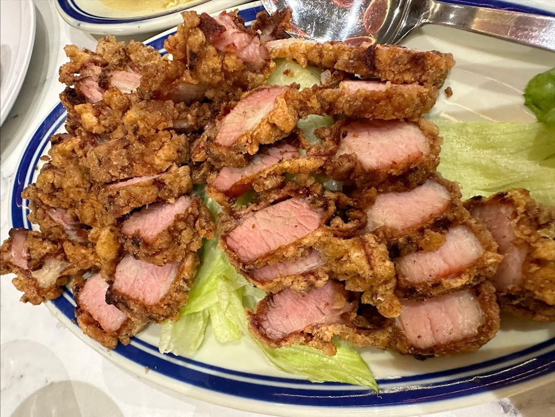 A plate of crispy fried pork slices with lettuce on a white and blue rimmed plate.