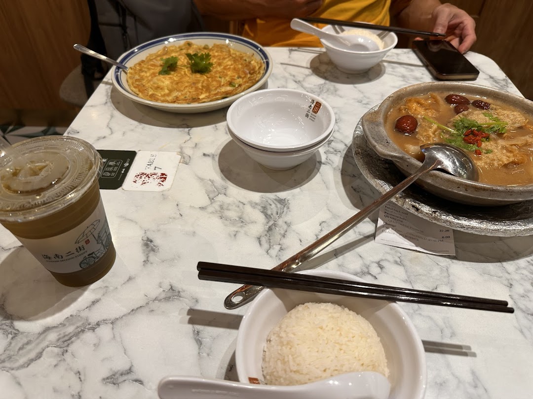 A table with various dishes, drinks, and a person's hands in a restaurant setting.