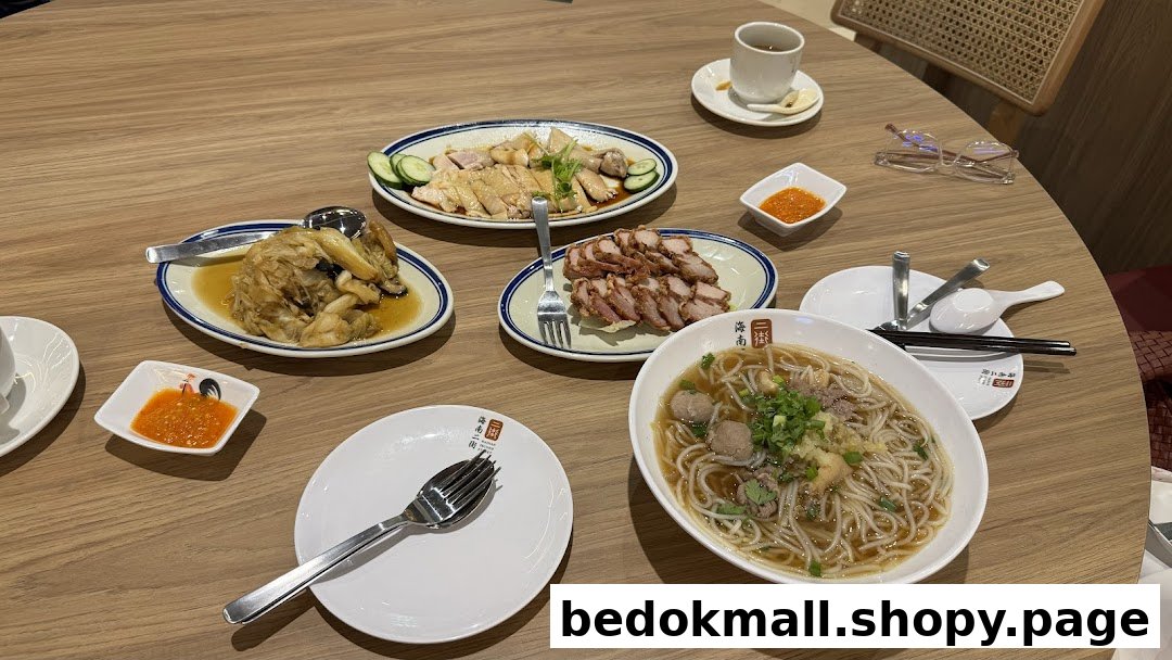 Table with multiple dishes of Hainanese food, including chicken, char siu, and noodles.