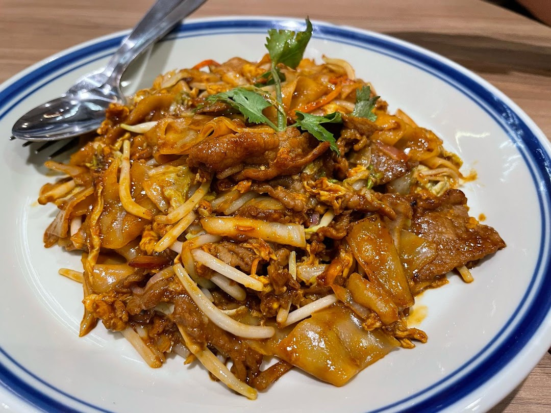 A close-up of a plate of stir-fried noodles with meat and vegetables.