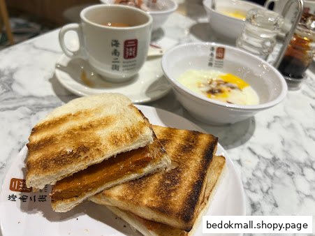A plate of kaya toast, a cup of tea, and soft-boiled eggs on a table.