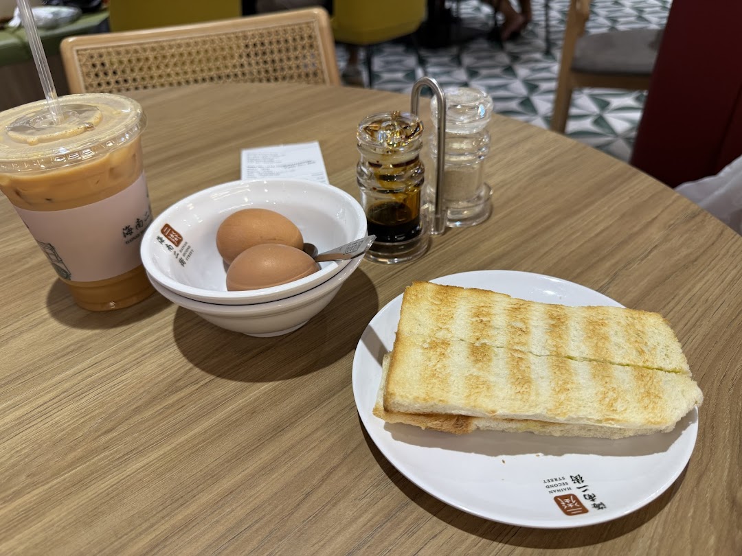 A breakfast set with toast, soft-boiled eggs, and an iced drink on a wooden table.
