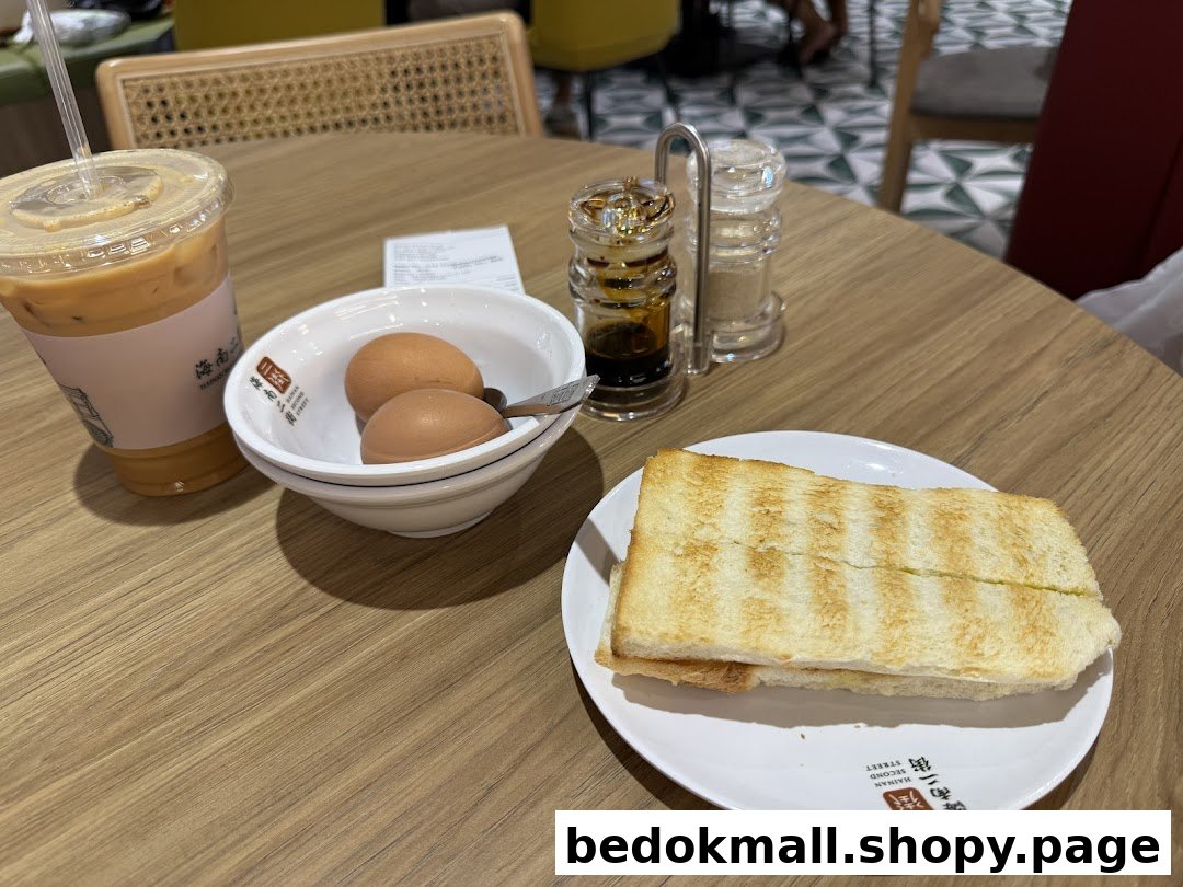 A breakfast set with toast, soft-boiled eggs, and an iced drink on a wooden table.